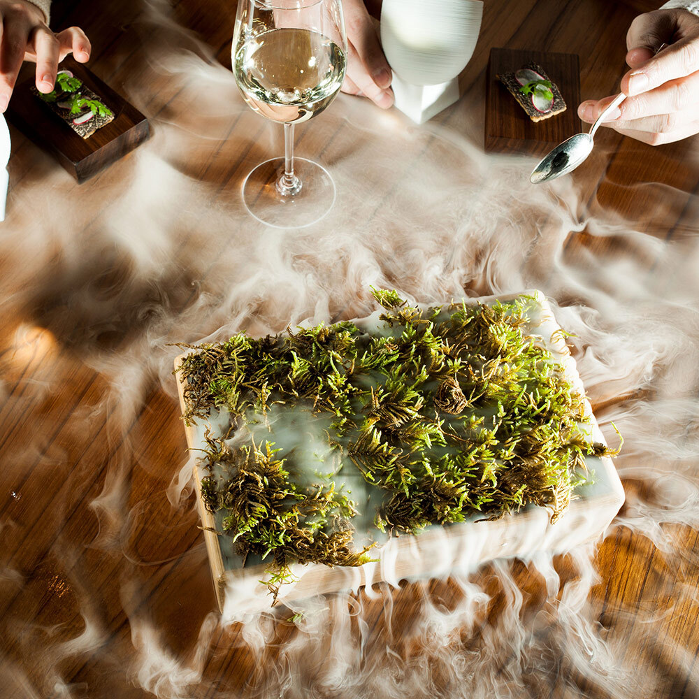 A box of oak moss through a cloud of moss-scented steam on a dining table