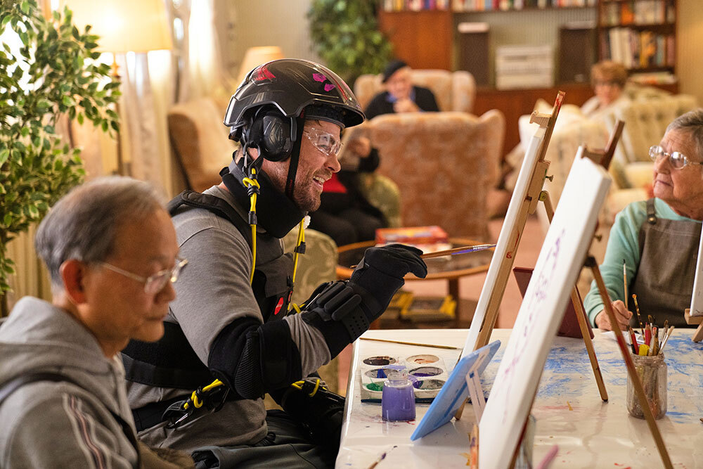 A picture of Chris Hemsworth painting in a suit with bungee cords attached