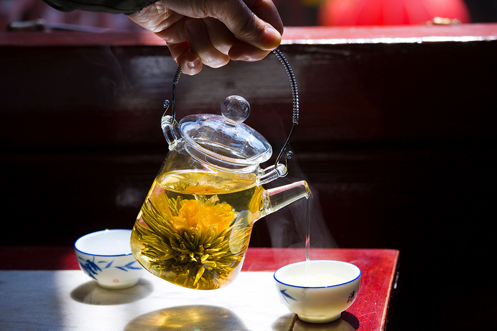 Herbs being poured from steamy water in a kettle