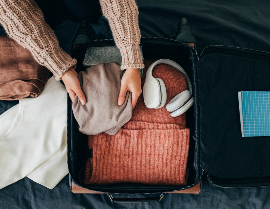 Happy traveller: a woman packing her clothes into a suitcase, getting ready for a trip.