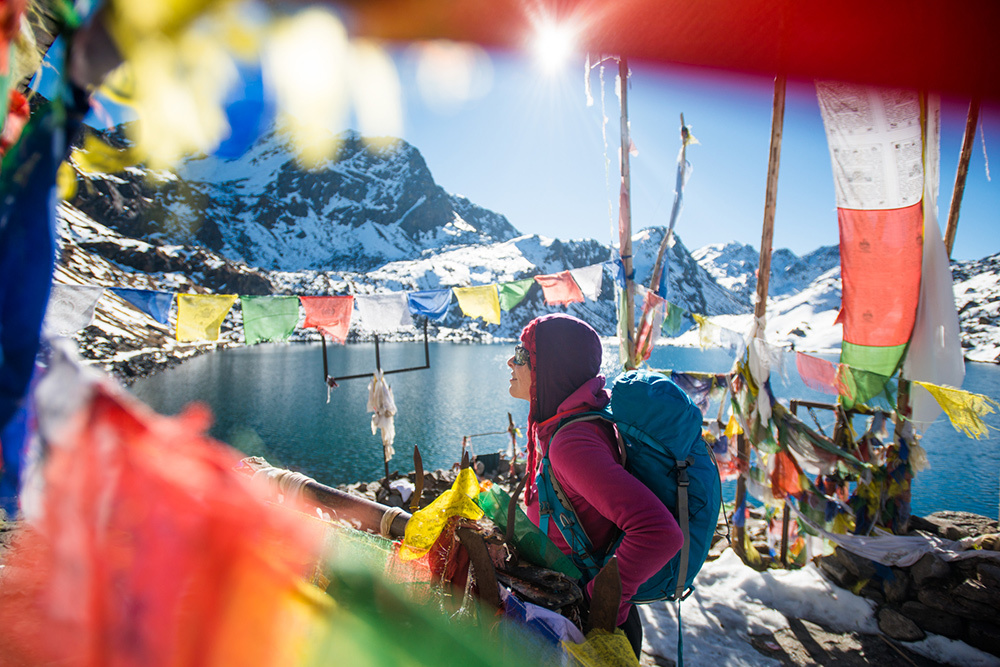 A trekker stands among prayer flags beside the holy lakes at Gosaikund in the Langtang region of Nepal