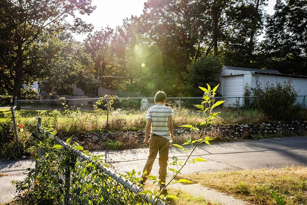 A child stands outside near a driveway.