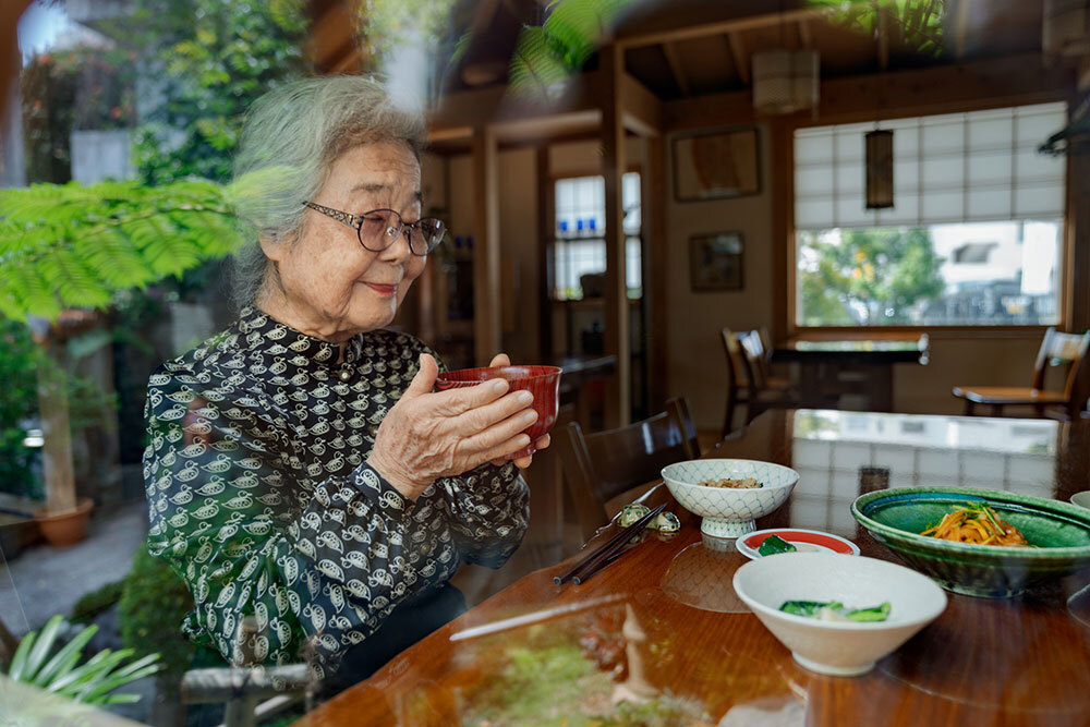 An older woman eats out of a bowl