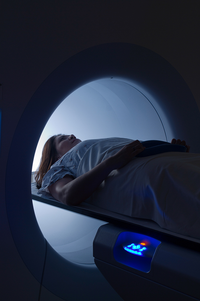 A close-up view of a woman laying on her back as she enters an MRI scanner.