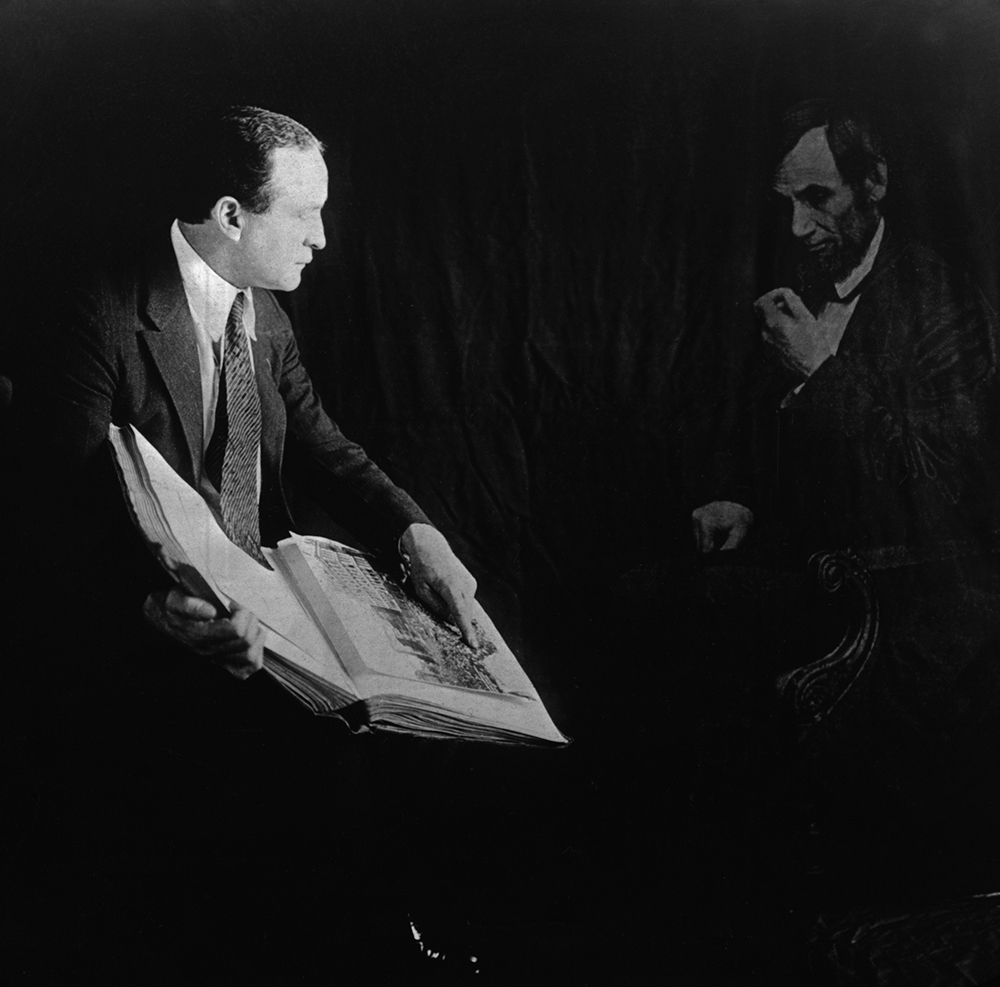 Harry Houdini showing a book to an image of Abraham Lincoln