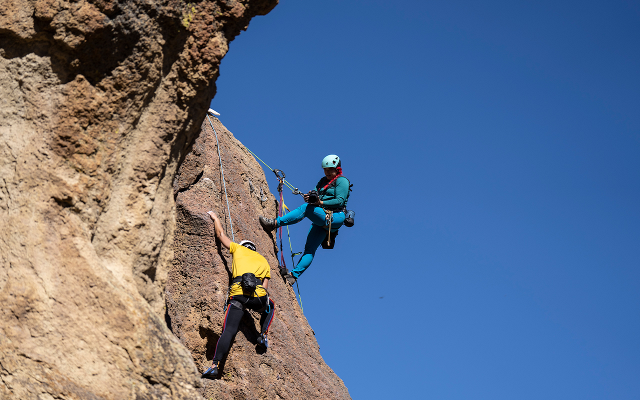 A photo of two people climbing a mountain.