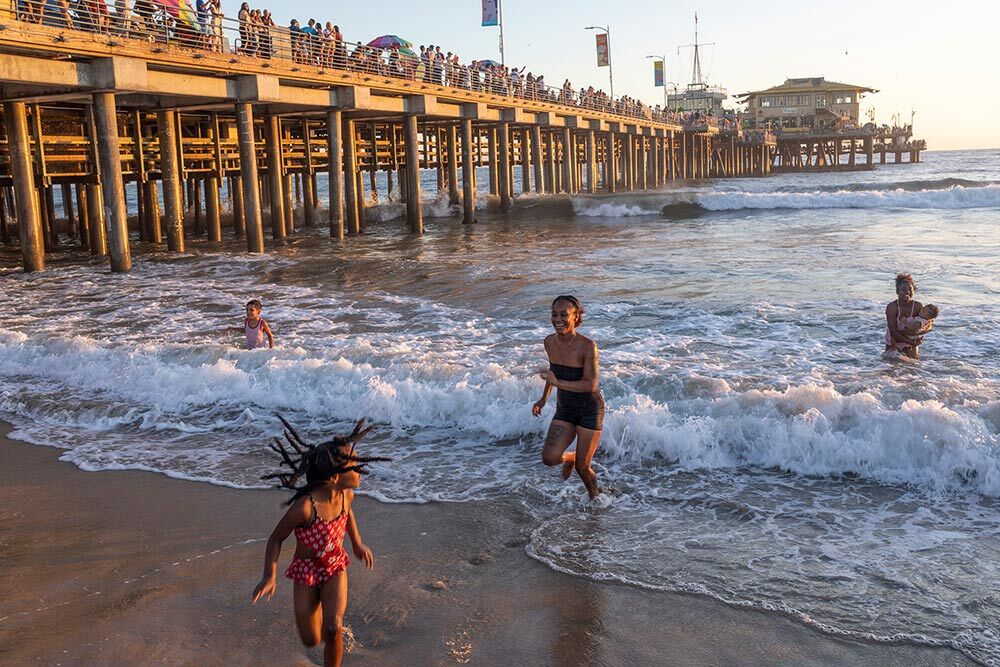 a family plays in the water next to the Santa Monica Pier