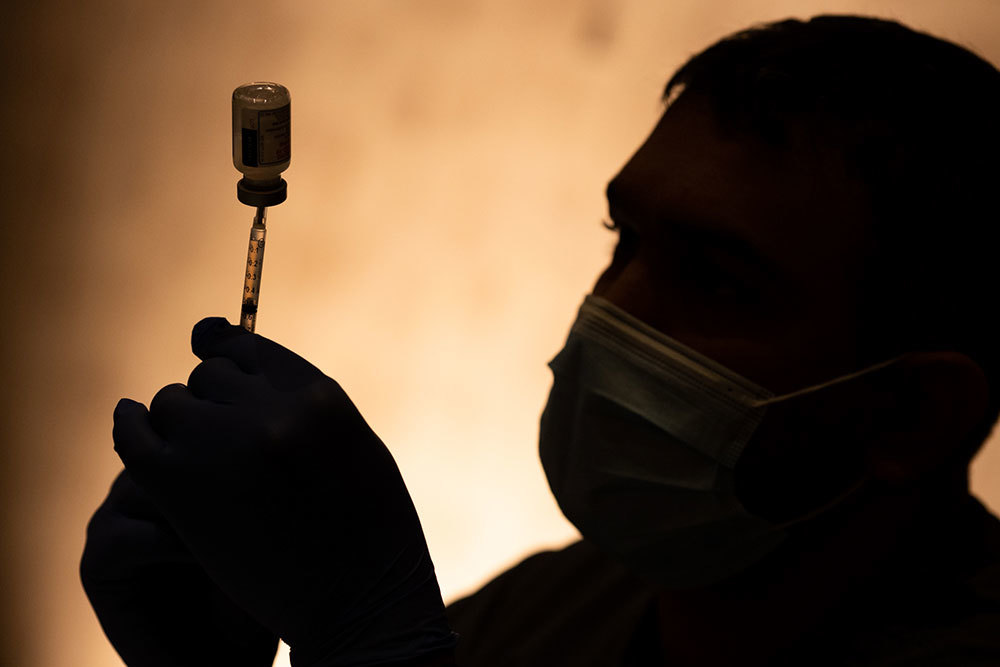 An picture of a person using a needle to extract liquid from a bottle