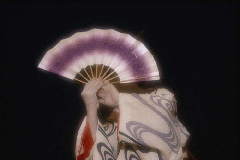 An geisha holds a fan in front of her face during a formal ceremony in Kyoto, Japan