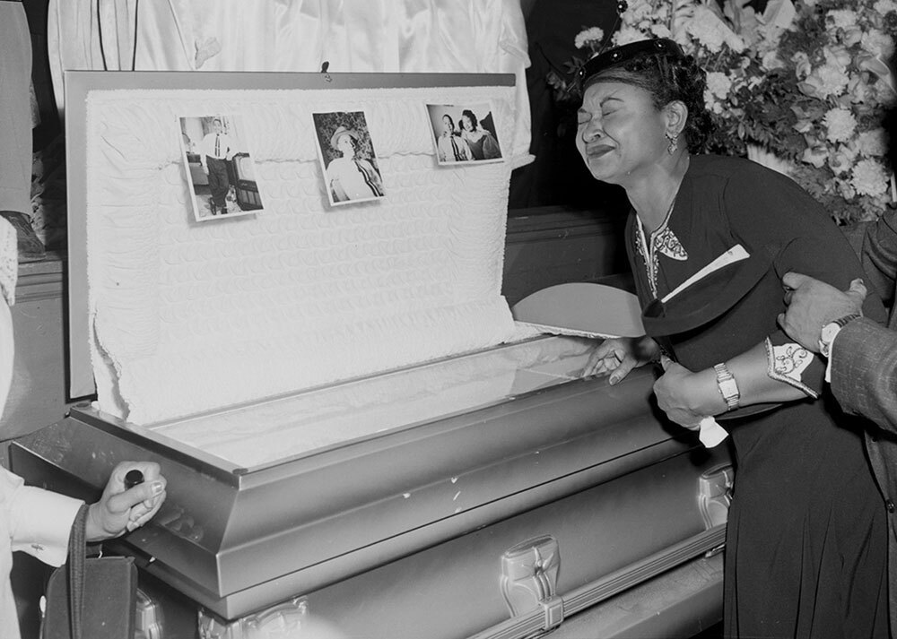 A woman grieves at the side of an open casket