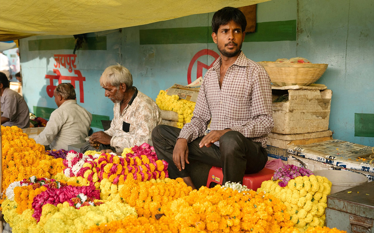 Flower seller's booth filled with yellow, orange, and pink flowers