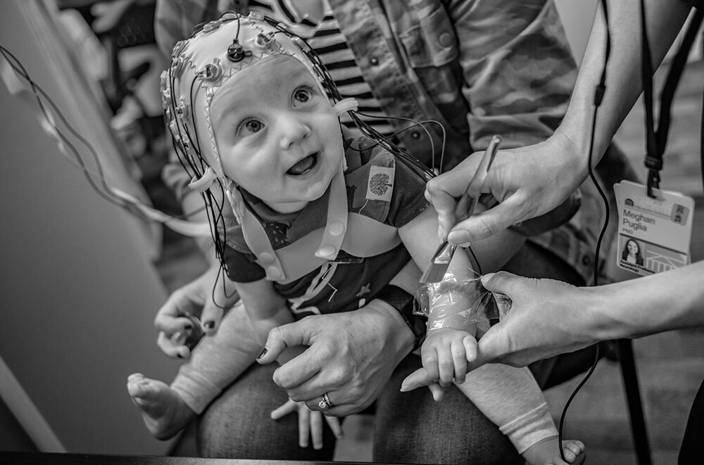 A toddler wears a cap connected to cables to monitor brain activity