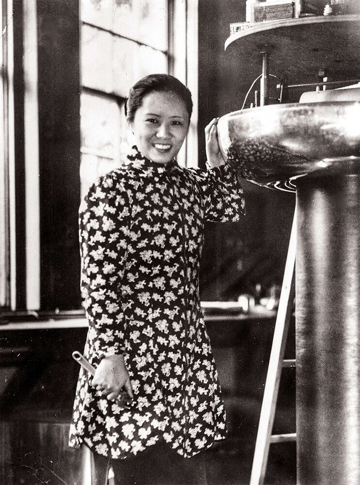 a black and white photo of a Chinese-American woman standing next to an electrostatic generator