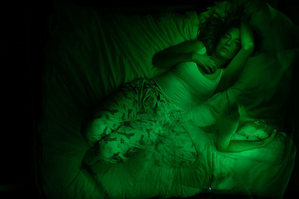 A picture of a woman in bed bathed in green light