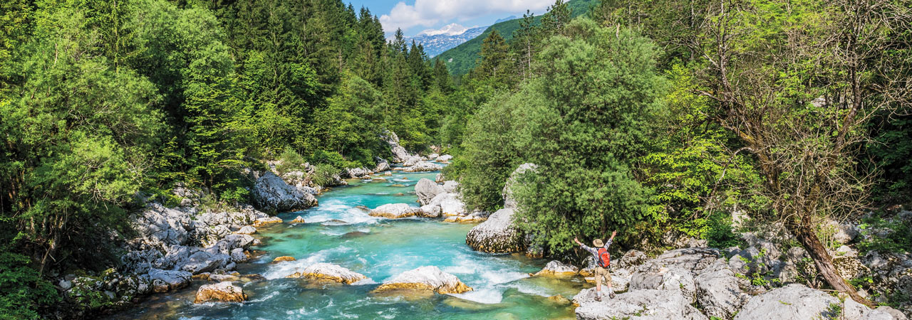 A hiker marvels at the emerald-blue waters of Slovenia's Soča Valley.