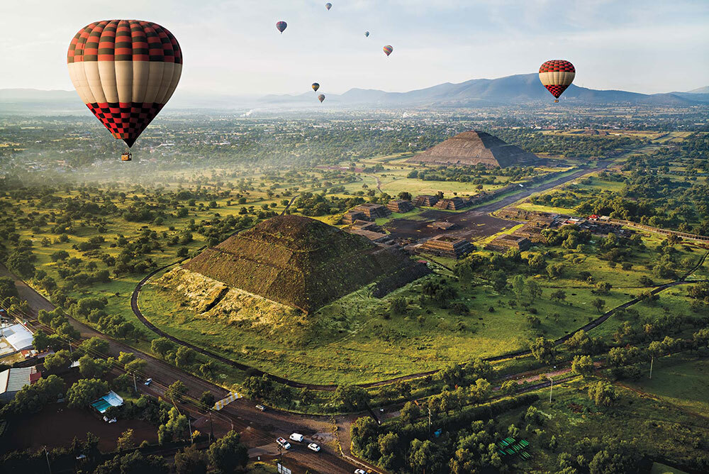 A photograph of hot air balloons rising over pyramids