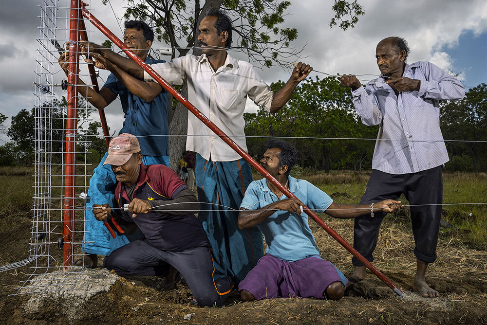 Villagers erect a solar-powered electric fence