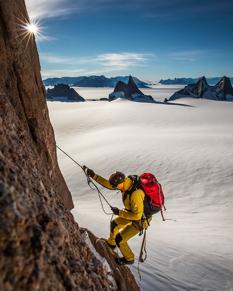 A climber hangs on a wall far above the ground