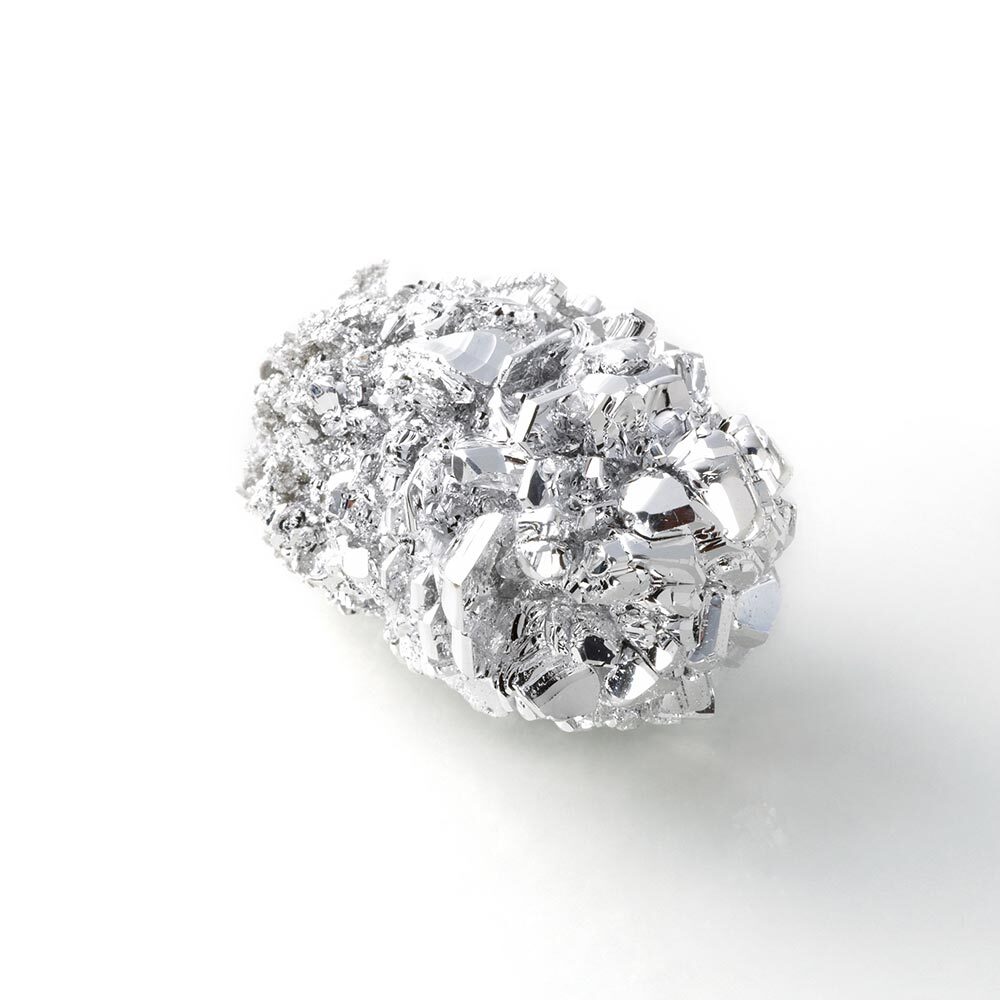 A sample of the earth metal Magnesium appears like a glossy, metal nugget.
