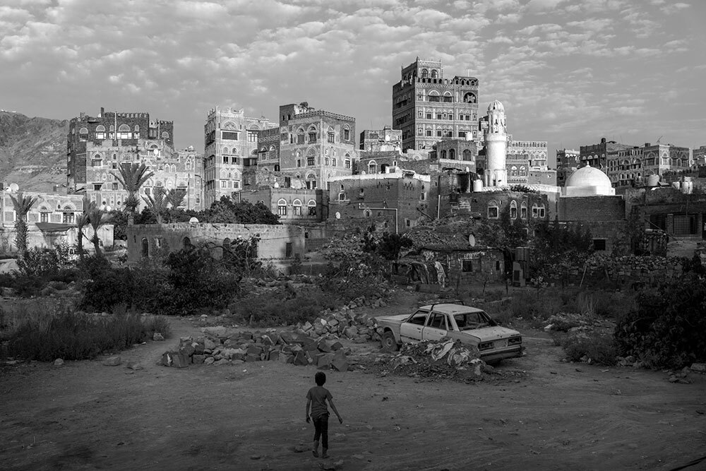 A picture of a boy in a dusty field with a city in the background