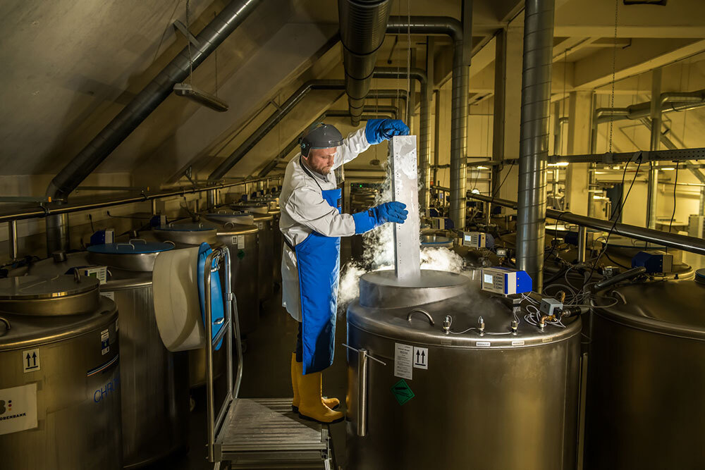 A person wearing gloves pull out a cold column from a large tank