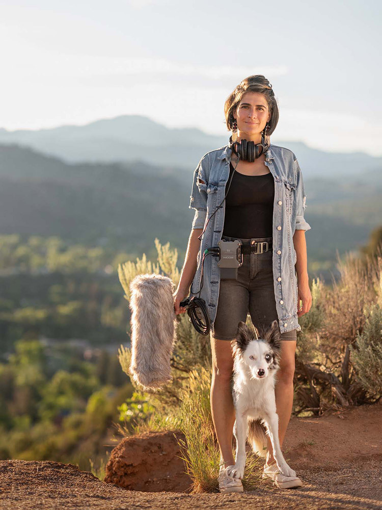 A woman holds a microphone with a dog at her feet