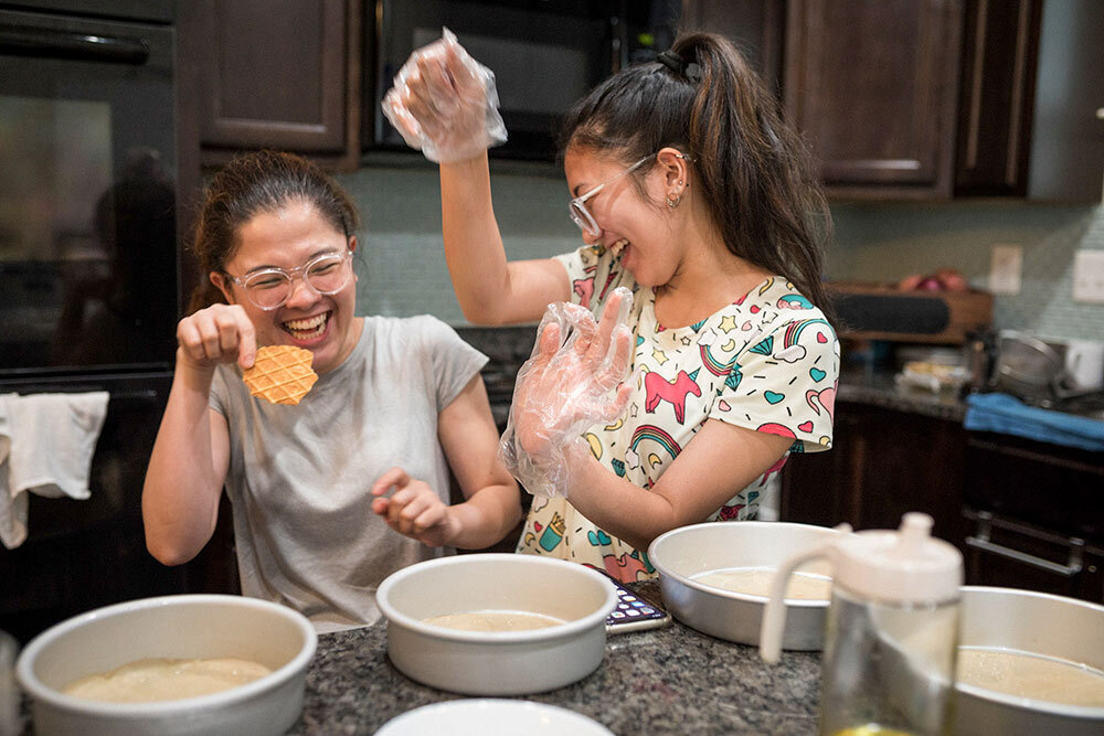 two sisters laugh while cooking together