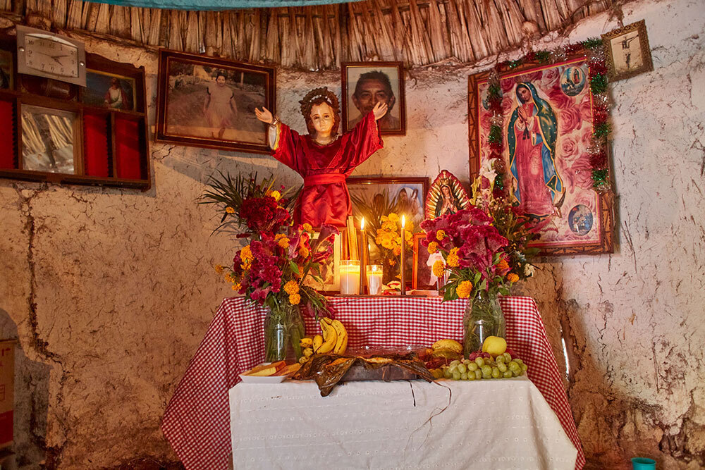 An alter with candles, religious figures, flowers, and fruits