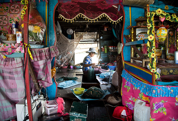 Yen fixes her fishing net on her boat. Most of the Vietnamese in Cambodia are stateless residents and live in floating settlements of dwelling zones on water which don't require citizenship papers.