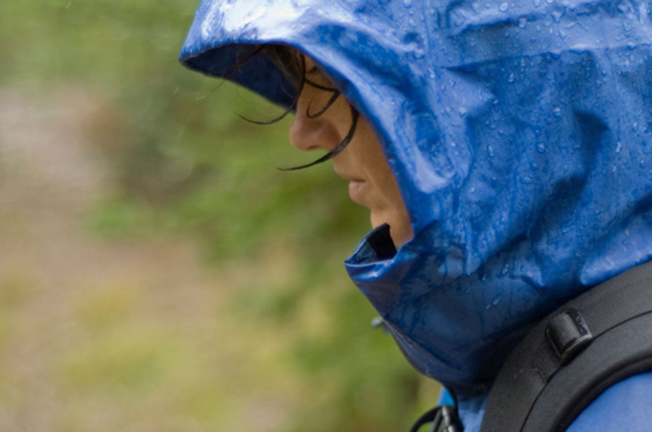 Woman in blue raincoat standing in the rain