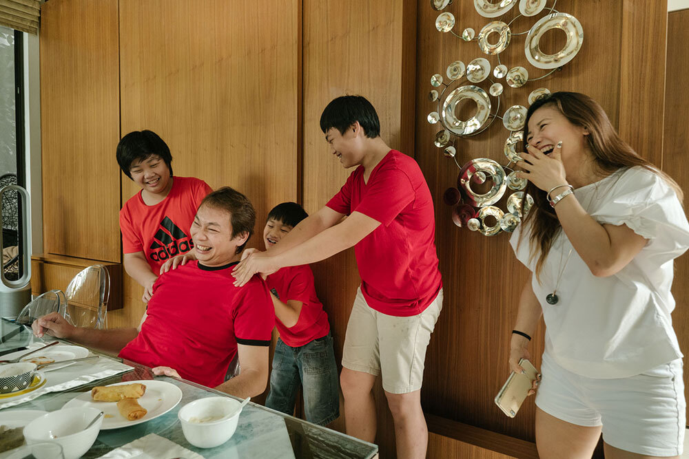 A family laughs while giving the father a back massage.