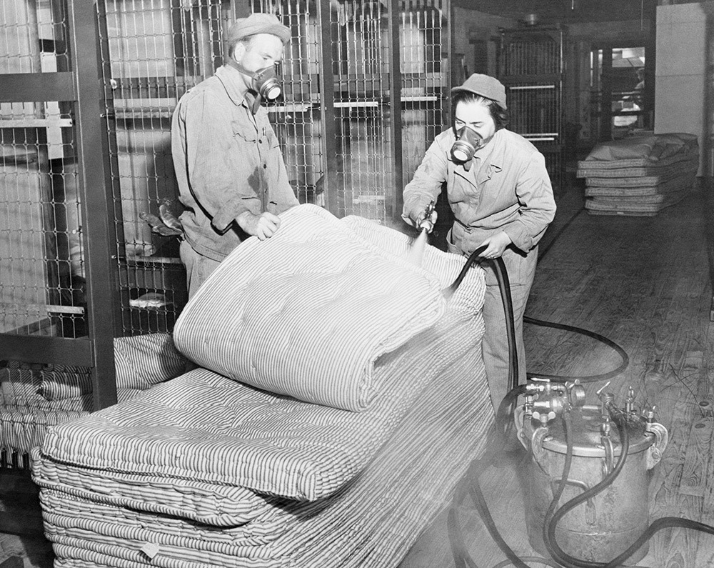 Workers spray mattresses at an Army barracks in 1944 with DDT solution that fights bedbugs. Note: location unknown