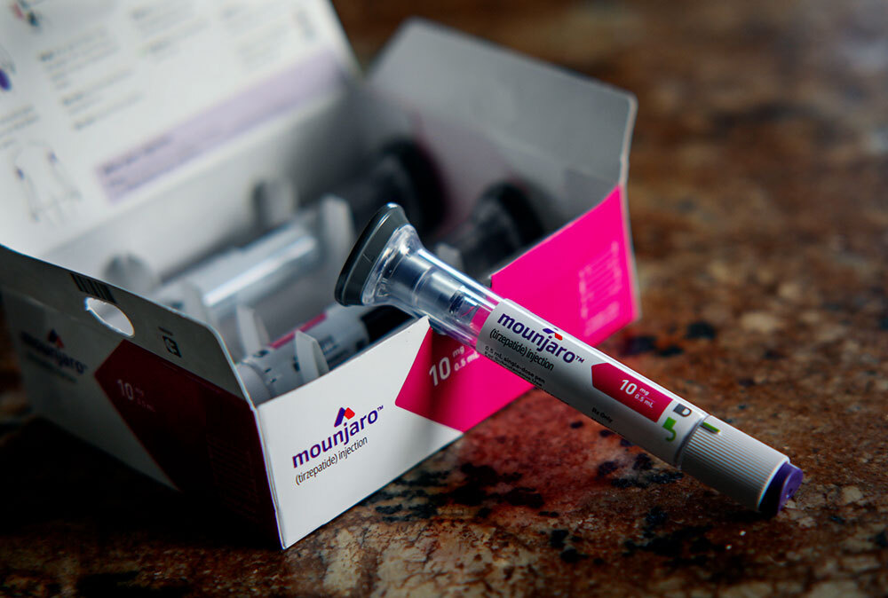 A Mounjaro injection pen on display next to its container