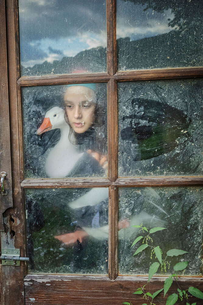 A girl in the window holding a duck