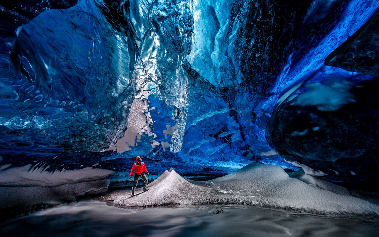 A visitor explores the ice caves within Vatnajökull Glacier. Because water from the glacier melts in the spring and freezes in the winter, the structure and condition of the caves change every year.