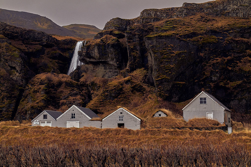 A picture of five houses with a waterfall in the background