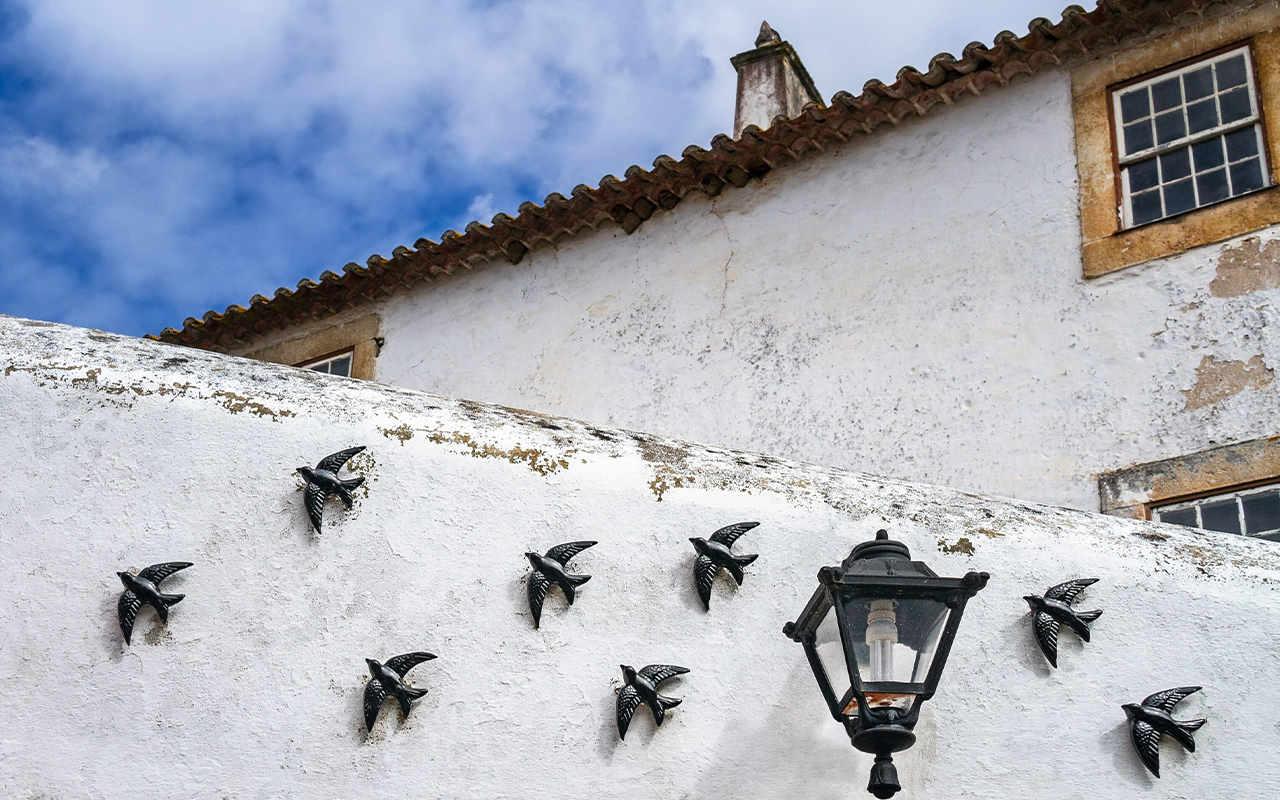 Black ceramic swallows decorate the wall of a home in Obidos, Portugal.