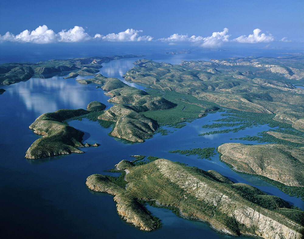 An aerial photo of hills jutting into a body of water