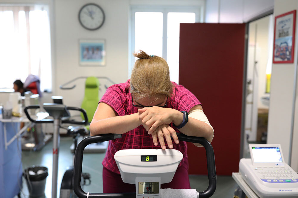 A patient suffering from chronic fatigue after being infected with COVID-19 takes a rest during rehabilitation exercises on a stationary bike.