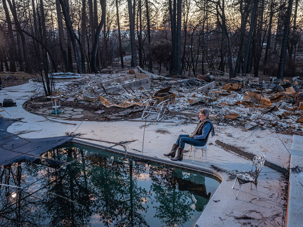 A woman sitting amid her house's ashes