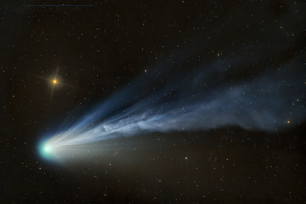 A bright blue comet and its cloud-like tail of particles, seen amongst the stars