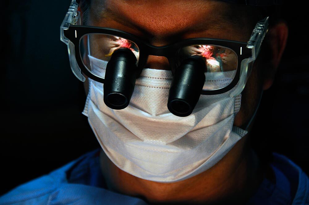 A close-up view of a surgeon's glasses reflecting the operating table during surgery.