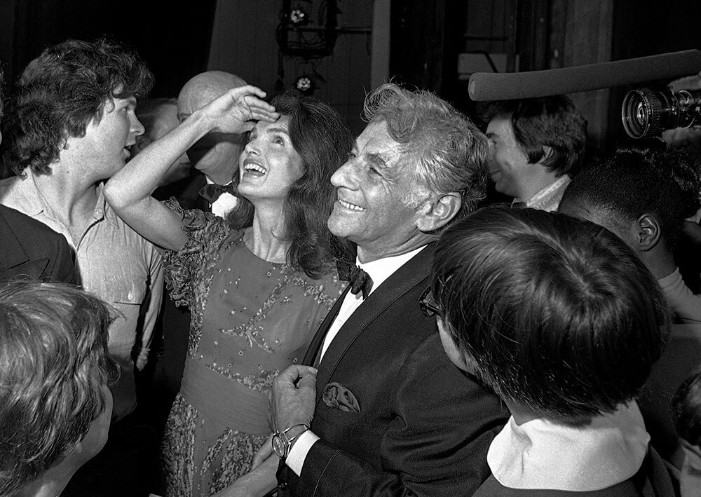 Jacqueline Kennedy Onassis stands with conductor-composer Leonard Bernstein while looking up at the stage in the John F. Kennedy Center for the Performing Arts, in Washington, DC.