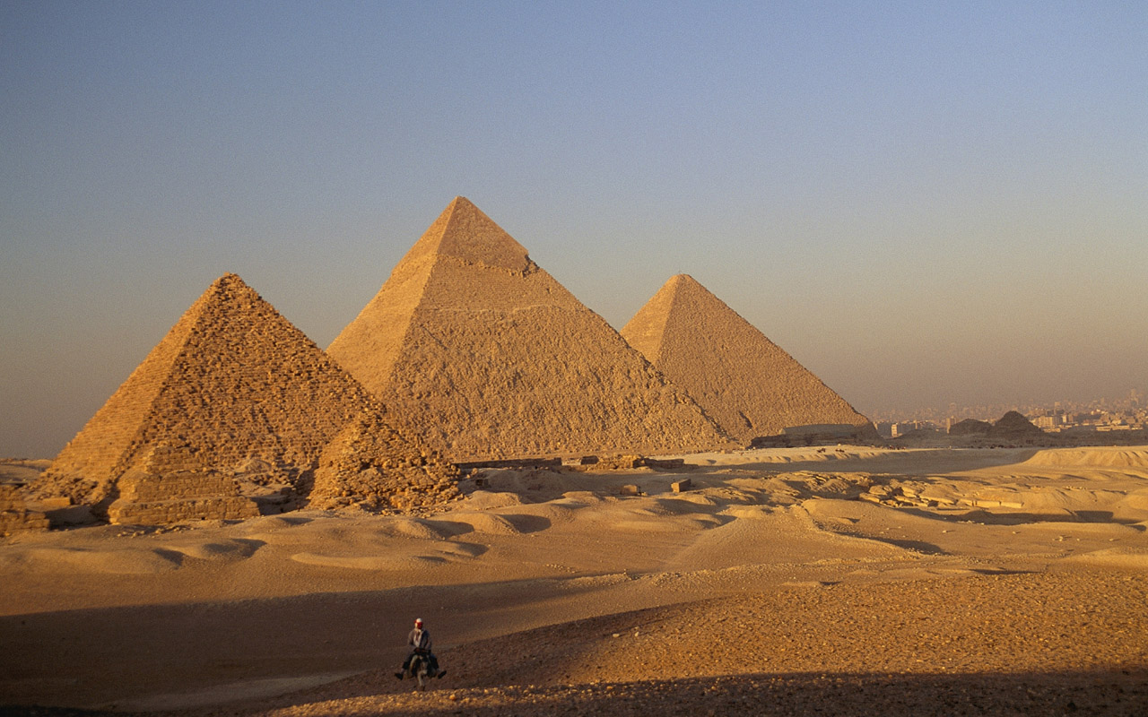 A man rides a donkey through the desert near the Great Pyramids of Giza. Modern technology is enabling scientists to peer inside these ancient Egyptian marvels—revealing hidden voids inside of them.
