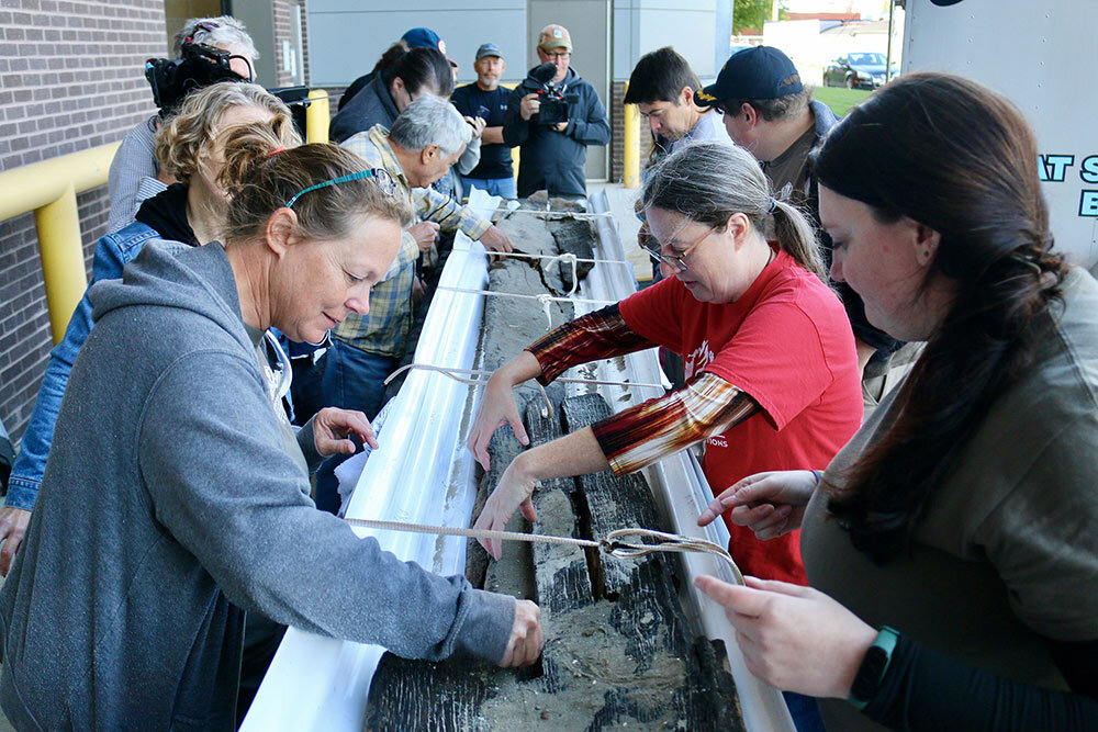 Wisconsin Historical Society maritime archaeologists Tamara Thomsen, left, and Caitlin Zant, right, and archaeologist Amy Rosebrough, second from right, carefully remove sediment from the canoe after it arrived at the State Archive Preservation Facility in Madison. Wisconsin Historical Society maritime archaeologists recovered a 3,000-year-old dugout canoe from Lake Mendota in Madison, Wisconsin, on Sept. 22, 2022.