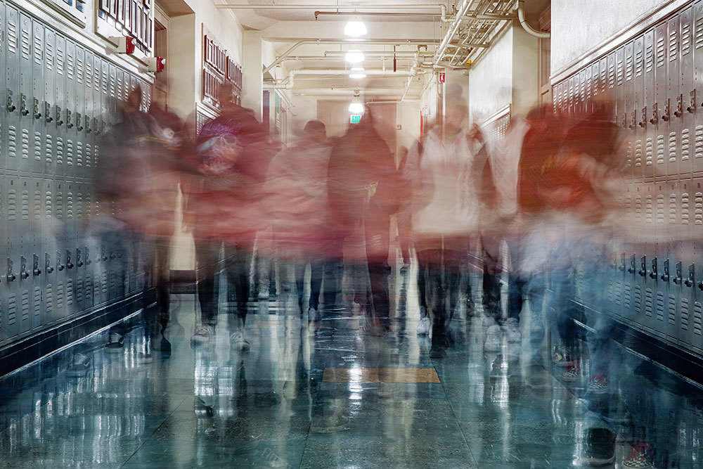 A long exposure photograph of students walking in a school hall