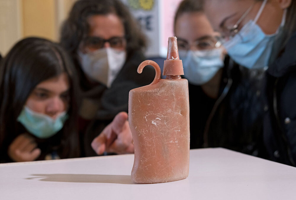 A picture of people looking at an oddly shaped plastic bottle