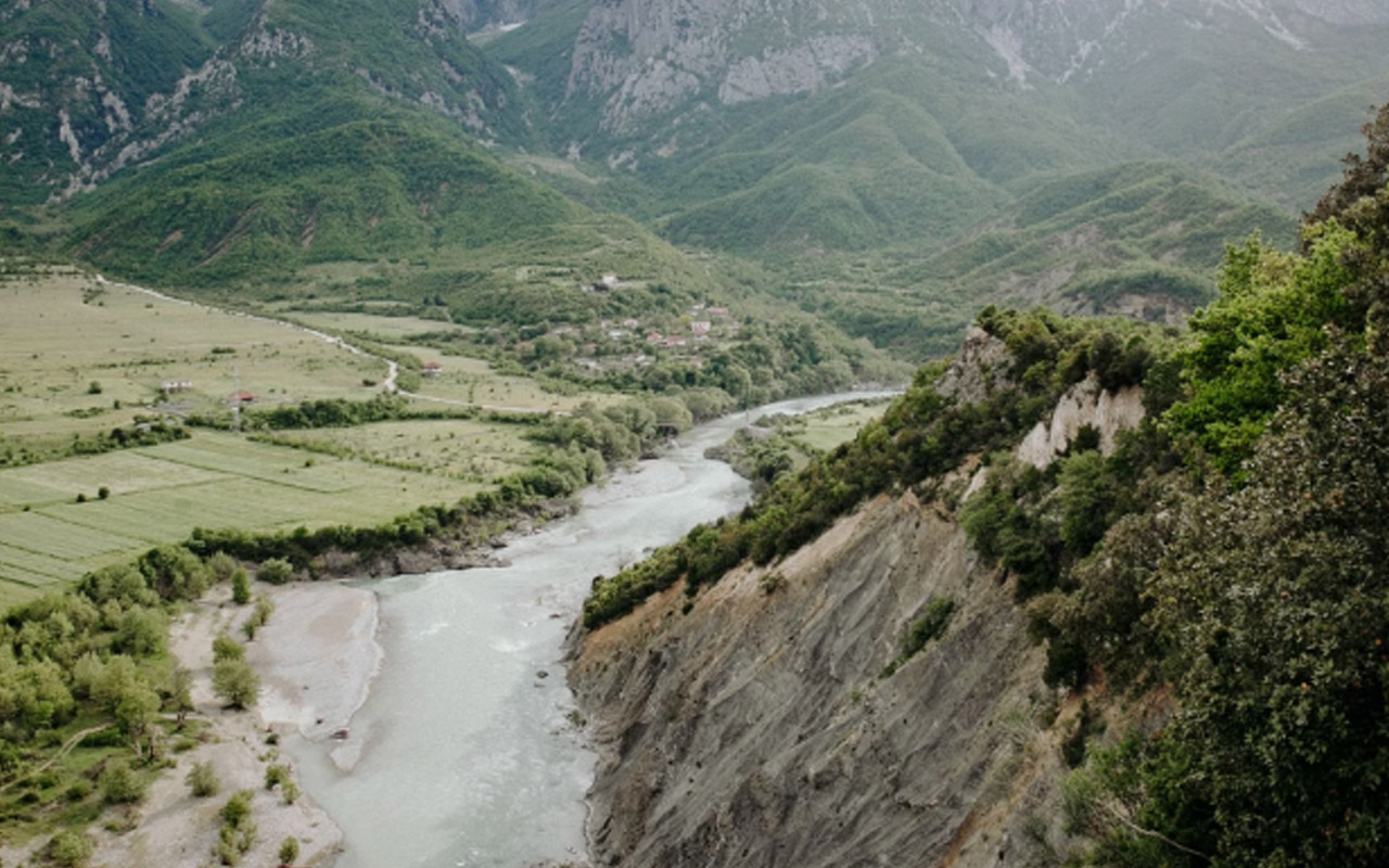 A view of a river surrounded by tall mountains in Albania.