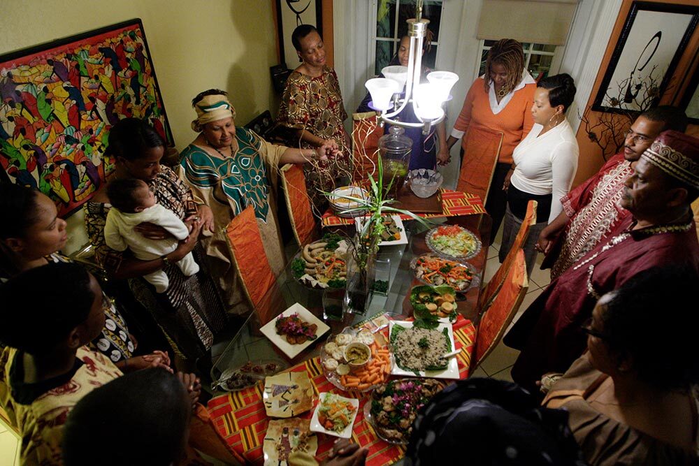 Friends and family join hands to share Kwanzaa blessings before eating special dishes prepared by Maisie McNaught at her home in Miami Gardens, Florida.