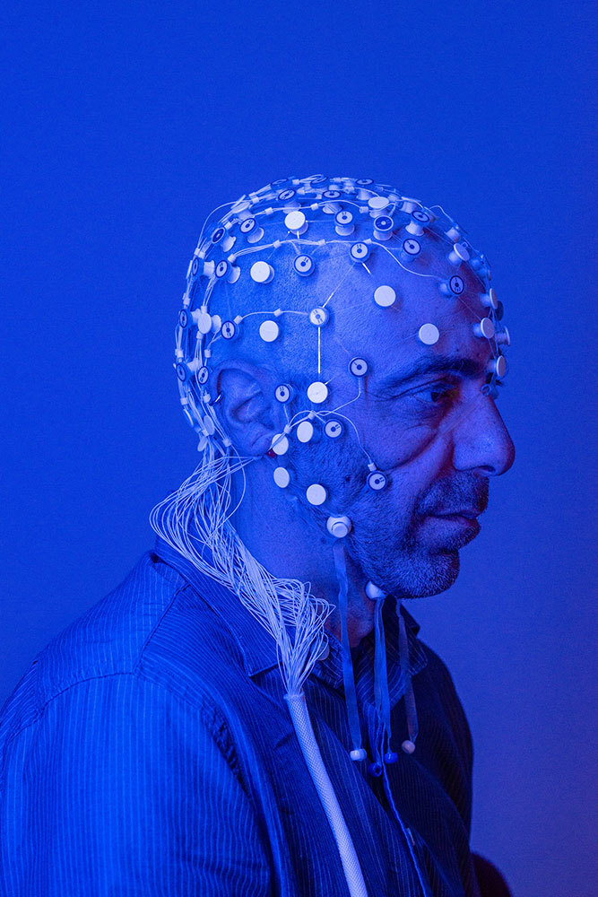 A picture of a man wearing a cap with nodes connected to his head